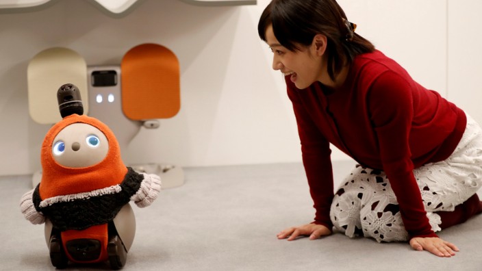 A woman calls up GROOVE X's new home robot LOVOT at its demonstration during the launching event in Tokyo