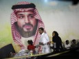 A Saudi family walk past a giant poster of Saudi Crown Prince Mohammed bin Salman