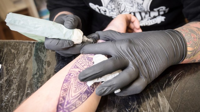Tattoo-Studio in der Corona-Krise: Gambino hilft beim Stechen der Stencil, eine lila-farbene Vorlage, die vor dem Tätowieren auf die Haut des Kunden übertragen wird.