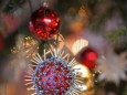 26.11.2020, Symbolbild, Am Weihnachstbaum im Wohnzimmer hängt ein Corona-Virus. Wegen der Corona-Pandemie könnte das Wei
