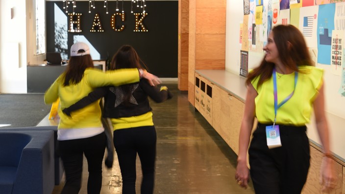 Tech-Konzerne: Cool möbliert, aber können die hier einfach so weiterarbeiten? Facebook-Mitarbeiterinnen laufen mit Schwung durch die Zentrale.