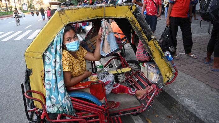 Philippinen: Diese Frau in Manila wartet auf ihren Mann, der bei einer Hilfsorganisation um Essen ansteht. Die Familie lebt in ihrer Rikscha.