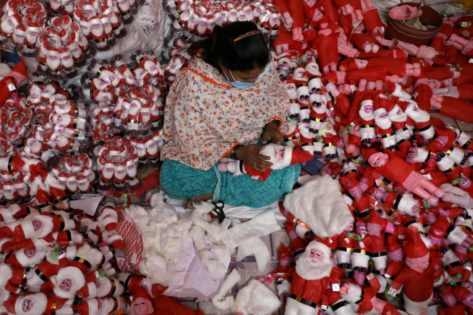 A woman makes models of Santa Claus inside her workshop ahead of Christmas, in Kolkata