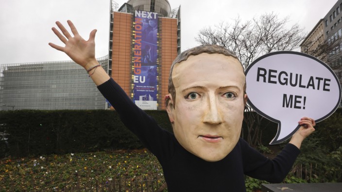 Digitalkonzerne: "Regulier mich", fordert dieser Demonstrant, der eine Maske mit dem Gesicht von Facebook-Chef Mark Zuckerberg trägt. Die EU möchte Facebook und Co. nun zumindest ein bisschen regulieren.
