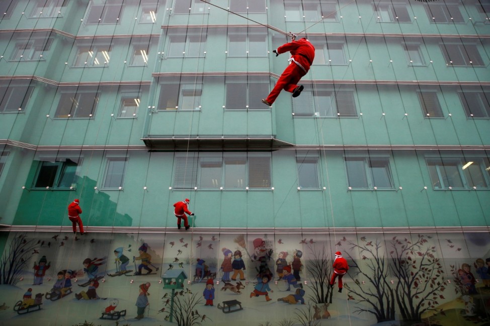 Rescuers dressed as Santa Clause repel down paediatric hospital in Ljubljana