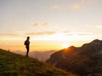 Germany Bavaria Oberstdorf man on a hike in the mountains looking at view at sunset model release