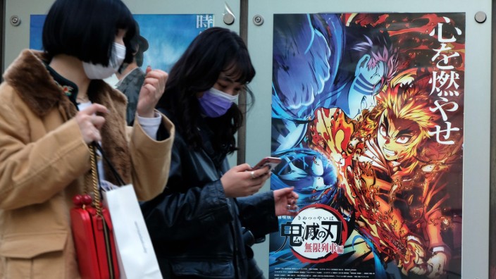 Aktuelles Lexikon: Fußgänger in Tokio vor einem Plakat, das den Anime-Film "Demon Slayer" bewirbt. Er basiert auf einer Manga-Reihe.