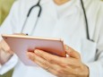 Arzt in Klinik schaut nutzt App auf Tablet Computer