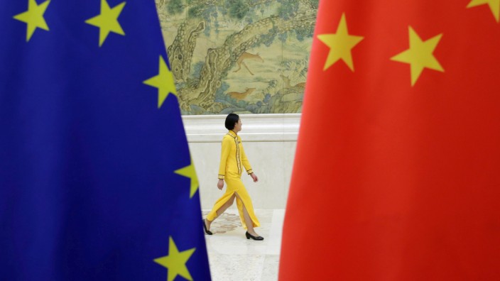 FILE PHOTO: An attendant walks past EU and China flags ahead of the EU-China High-level Economic Dialogue in Beijing