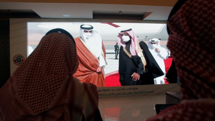 Journalists watch a screen showing the Saudi Arabia's Crown Prince Mohammed bin Salman welcoming Qatar's Emir Sheikh Tamim bin Hamad al-Thani upon his arrival to attend the Gulf Cooperation Council's (GCC) 41st Summit, at the media centre in Al-Ula