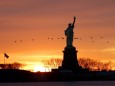 The sun rises behind the Statue of Liberty from Liberty State Park in Jersey City, New Jersey on Monday, January 11, 20