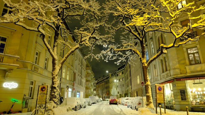 München heute: Münchens verschneite Straßen leuchten elegant im Licht der Laternen, die Nacht wirkt wie verzaubert.