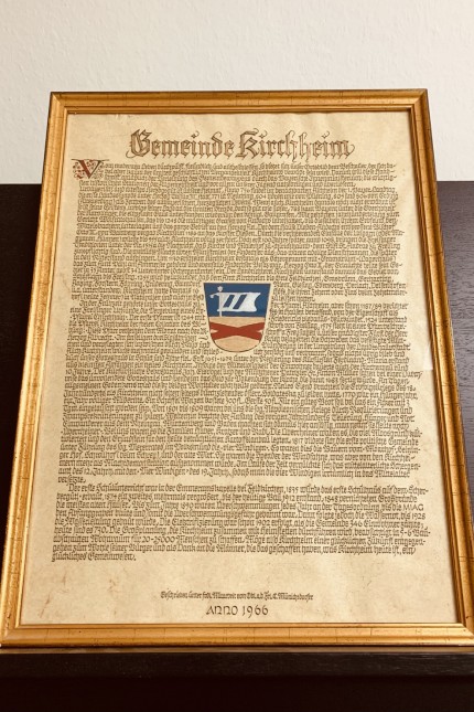 Kirchheim: Die Handschrift zeigt noch das alte Wappen Kirchheims, das nach der Gebietsreform um Elemente aus dem Heimstettener Wappen ergänzt wurde.