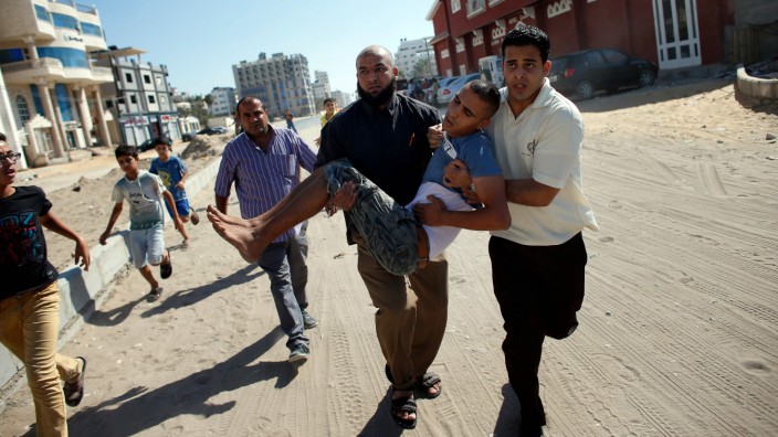 Nahostkonflikt: Palästinenser tragen im Gazastreifen nach einem israelischen Militärschlag im Jahr 2014 einen verwundeten Jungen weg.