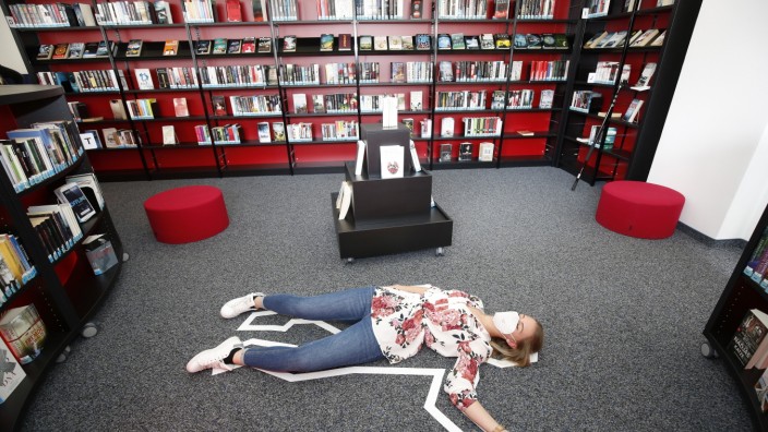 Literatur in Geretsried: Rollenspiel für die Kamera: Bücherei-Mitarbeiterin Laura Diebel stellt sich als Mordopfer in der neuen Krimiabteilung zur Verfügung.