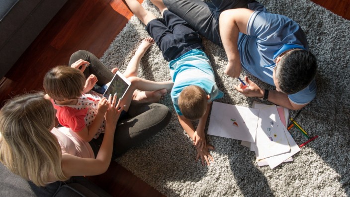 Happy Young Family Playing Together at home on the floor using a tablet and a children’s drawing set top view,mode