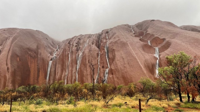 Waterfalls tumble over the surface of Uluru in the Northern Territory, Australia