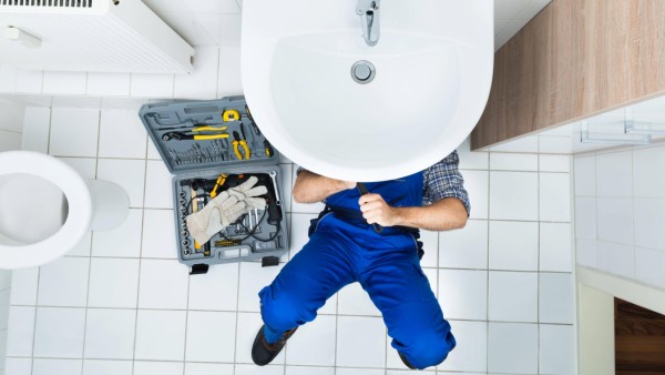 High Angle View Of Male Plumber Repairing A Sink In Bathroom model released Symbolfoto PUBLICATIONxI
