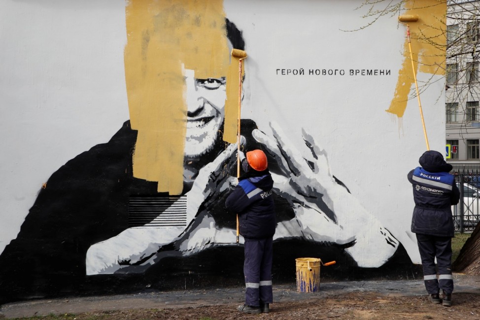 Workers paint over a graffiti depicting Alexei Navalny in Saint Petersburg