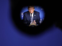 President Donald Trump, seen through a video camera s eyepiece, attends a coronavirus roundtable briefing at the Nation