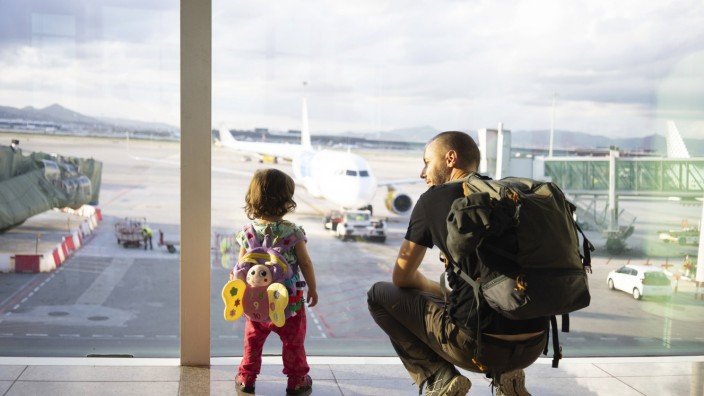 Father and daughter with backpacks at the airport looking at the planes model released Symbolfoto PU