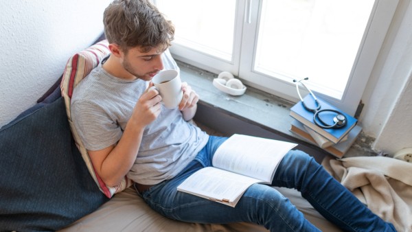 Studieren auf der Couch - gemütlich mit Tee und Lehrbuch zu Hause fürs Studium lernen - Deutschland *** Study on the cou