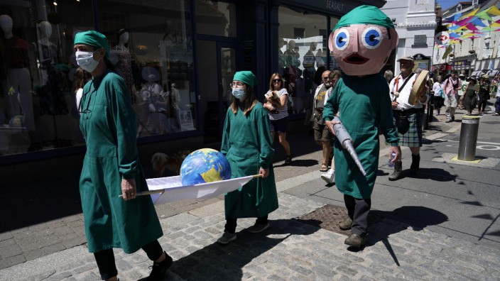 G 7 und Klimaschutz: Mit einer Protestaktion in Falmouth, Cornwall, werfen Demonstranten als medizinisches Personal verkleidet den Staaten vor, zu wenig für Klima und Umwelt zu tun.