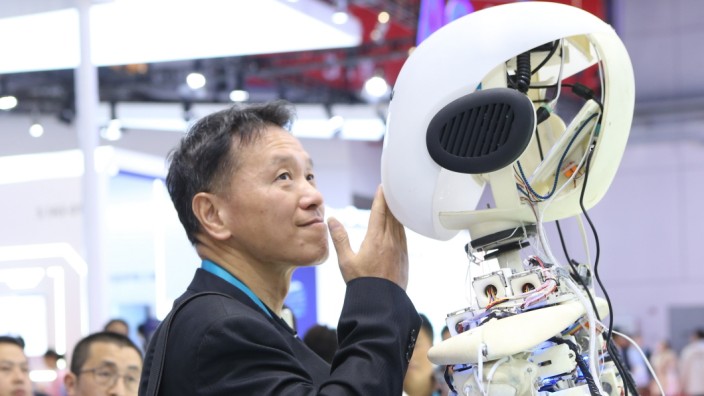 Weltwirtschaft: Ein Messe-Besucher posiert in Shanghai mit Roboy, einem Roboter-Forschungsprojekt, das vom Münchner Technologieunternehmens Infineon unterstützt wurde.