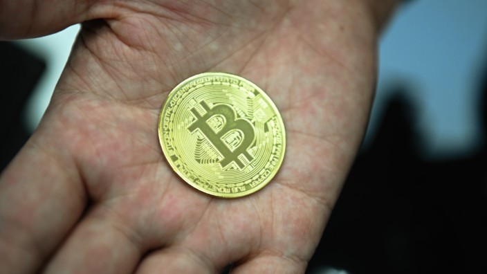 Migration und Geld: Ein Mann hält eine nachgemachte Münze mit dem Bitcoin-Logo in den Händen. El Salvador will die Kryptowährung Bitcoin zu einem gesetzlichen Zahlungsmittel machen.