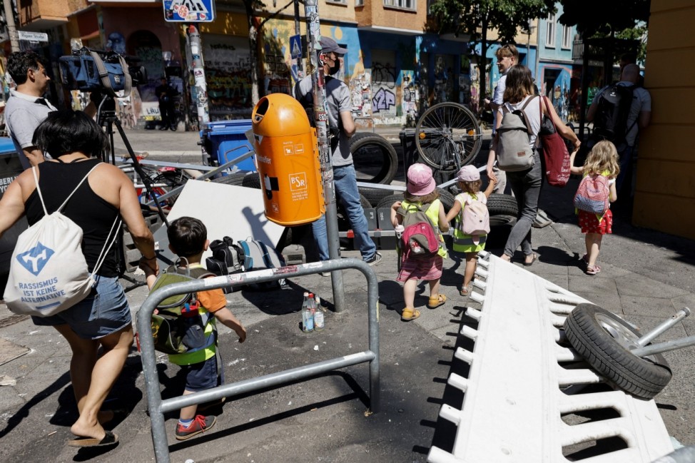 A group of children walk near extinguished barricades at Rigaer Street in Berlin