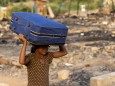 A Rohingya refugee carries her belongings to a temporary shelter after a fire destroyed a Rohingya refugee camp on Saturday night, in New Delhi