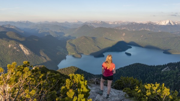 Junge Frau steht am Gipfel, Ausblick vom Herzogstand auf Walchensee und Alpen, Oberbayern, Bayern, Deutschland, Europa *