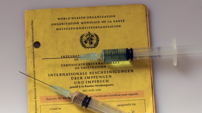 Coronavirus: Ein Impfpass liegt auf einem Tisch mit zwei Spritzen