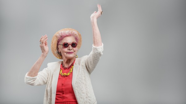 I want to move. Happy stylish senior lady in hat dancing with hands raised and smiling isolated on gray background (YakobchukOlena)