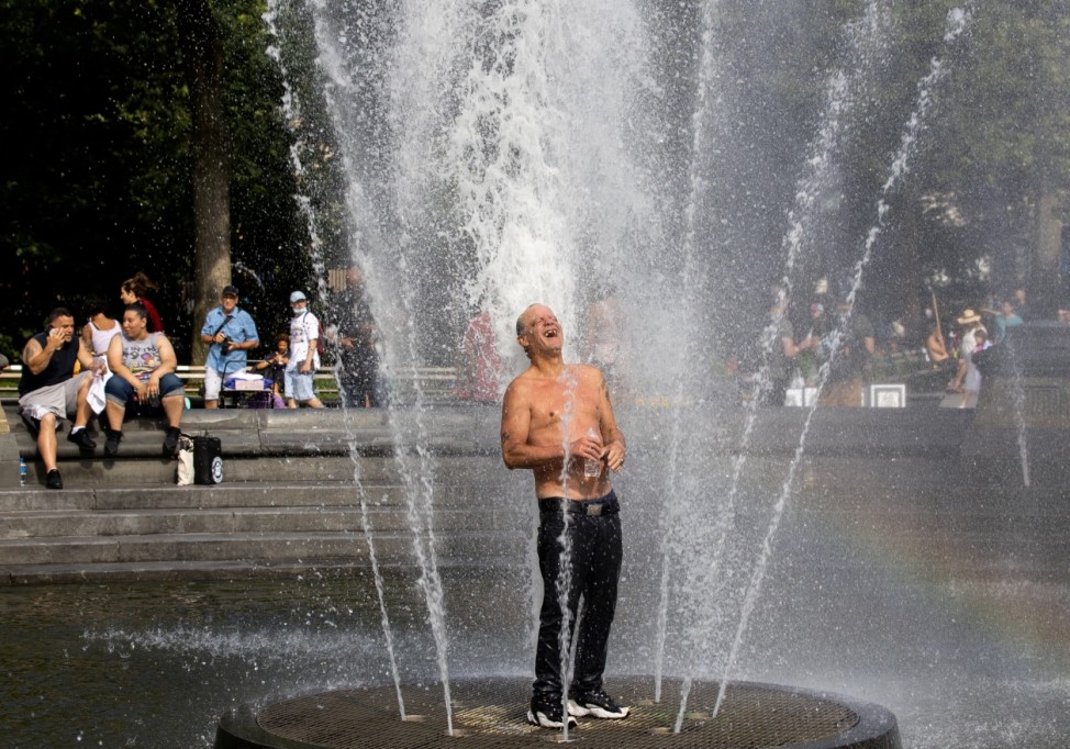 A man cools off himself on a fountain during a heat wave in New York City