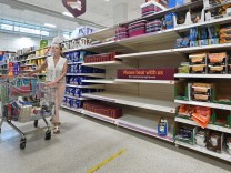 Corona in England: Eine Frau steht vor leeren Supermarktregalen