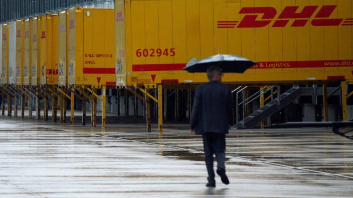 A pedestrian walks past a distribution centre of German postal and logistics group Deutsche Post DHL in Obertshausen