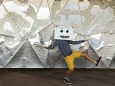 Boy wearing robot mask dancing on footpath against patterned wall model released Symbolfoto VABF03128