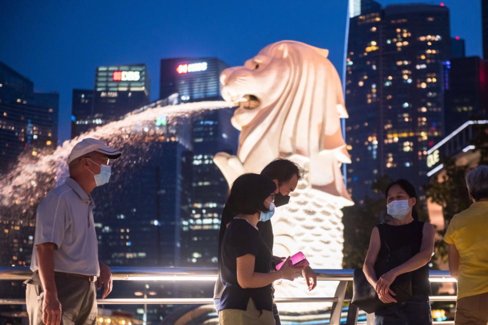 Virus Outbreak Singapore Vistors walk past the Merlion at the Marina Bay in Singapore on 18 July, 2021, the day before s