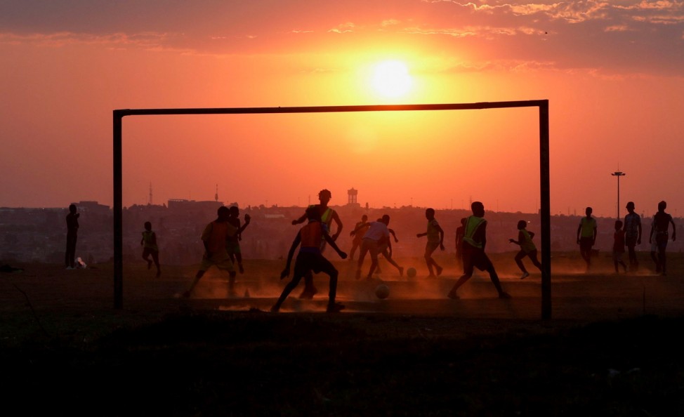 Locals play soccer on a dusty pitch in Soweto