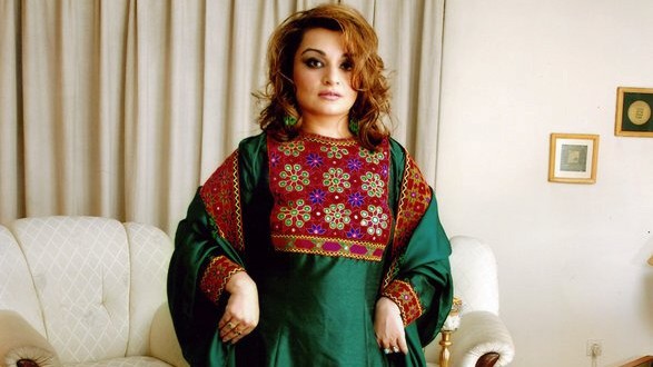 A woman poses in traditional Afghan attire, in Kabul