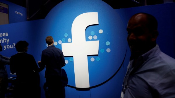 FILE PHOTO: Attendees walk past a Facebook logo during Facebook Inc's F8 developers conference in San Jose
