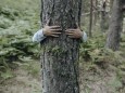 Man hugging tree in forest model released Symbolfoto JCCMF03799