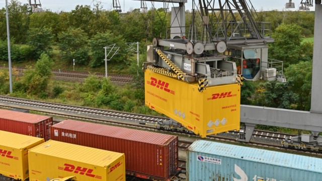 Güterverkehr: Ein Container von Deutsche Post DHL wird an einem Verladebahnhof in Großbeeren in Brandenburg vom Lkw auf einen Waggon der Deutschen Bahn gehoben.