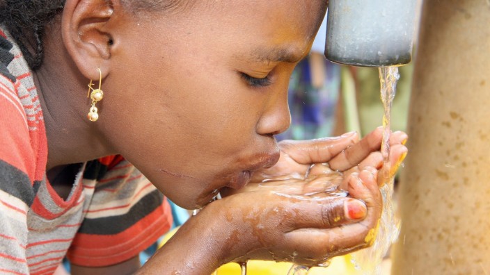 Trinkwasserknappheit: Ein Mädchen stillt ihren Durst an einer Quelle