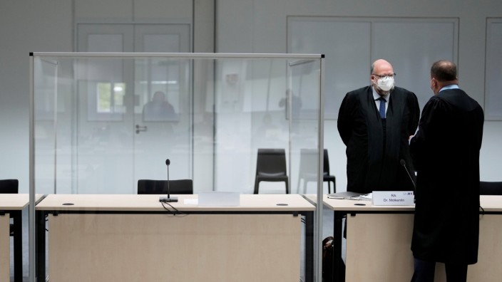 The defendant's lawyer Wolf Molkentin speaks to a man next to the empty seat of the accused 96-year-old former secretary to the SS commander of the Stutthof concentration, in Itzehoe