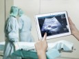 Hands holding digital tablet with ultrasound image in operating theatre model released Symbolfoto PUBLICATIONxINxGERxSU