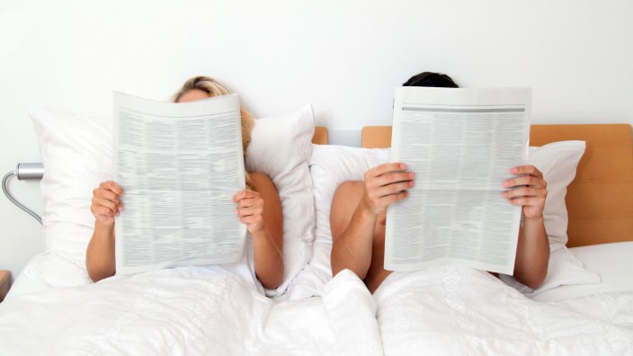 Ein junges Paar im Bett liest die Zeitung. Information und Nachrichten, McPBBO *** Young couple in bed reading the newsp