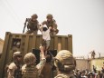 United Kingdom coalition forces, Turkish coalition forces, and United States Marines assist a child during an evacuation