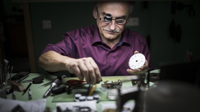 Ein Uhrmacher repariert eine Uhr in seiner Werkstatt Er traegt dabei eine Lupe Weisswasser 16 08